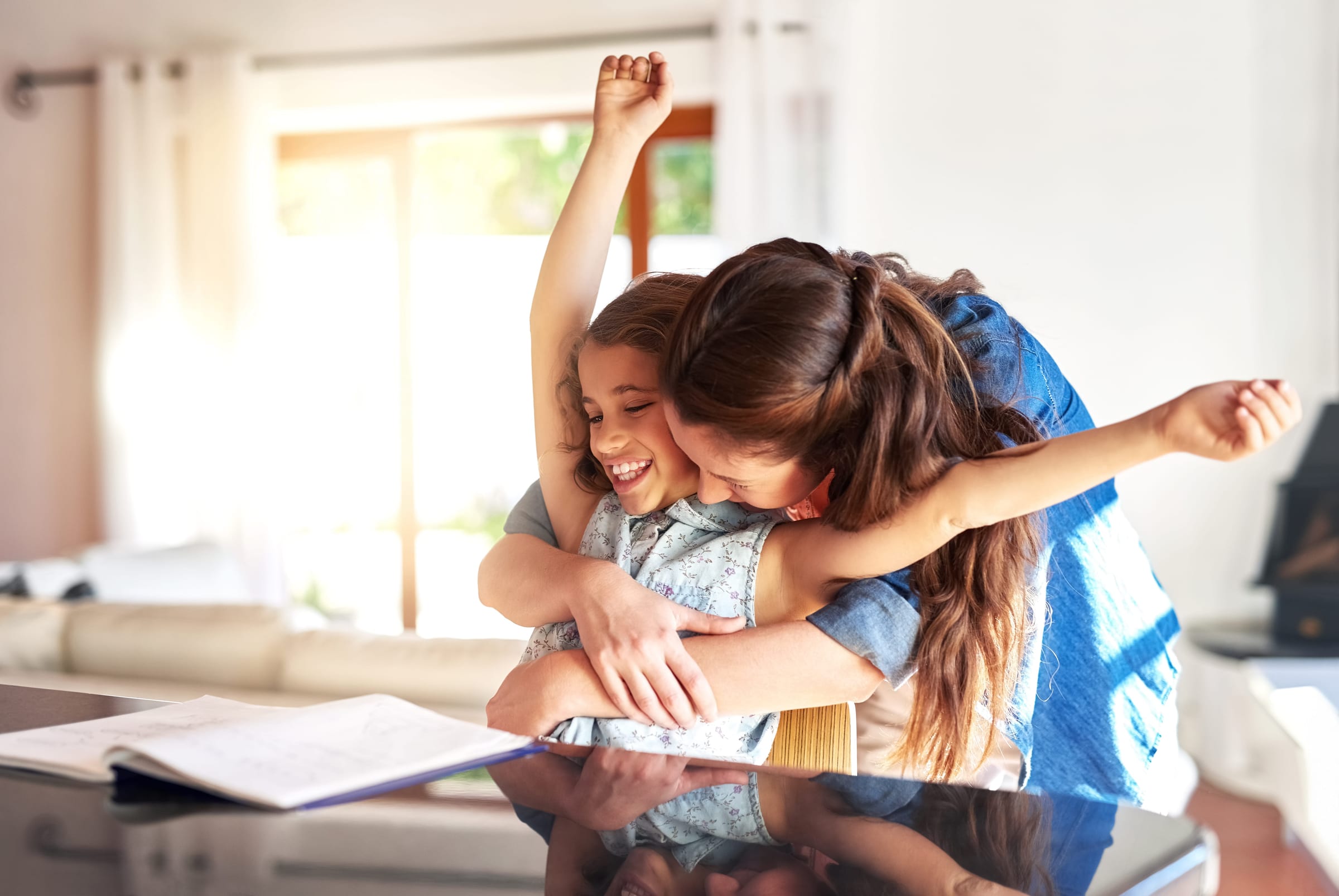 A parent and child hugging in celebration over a homework page