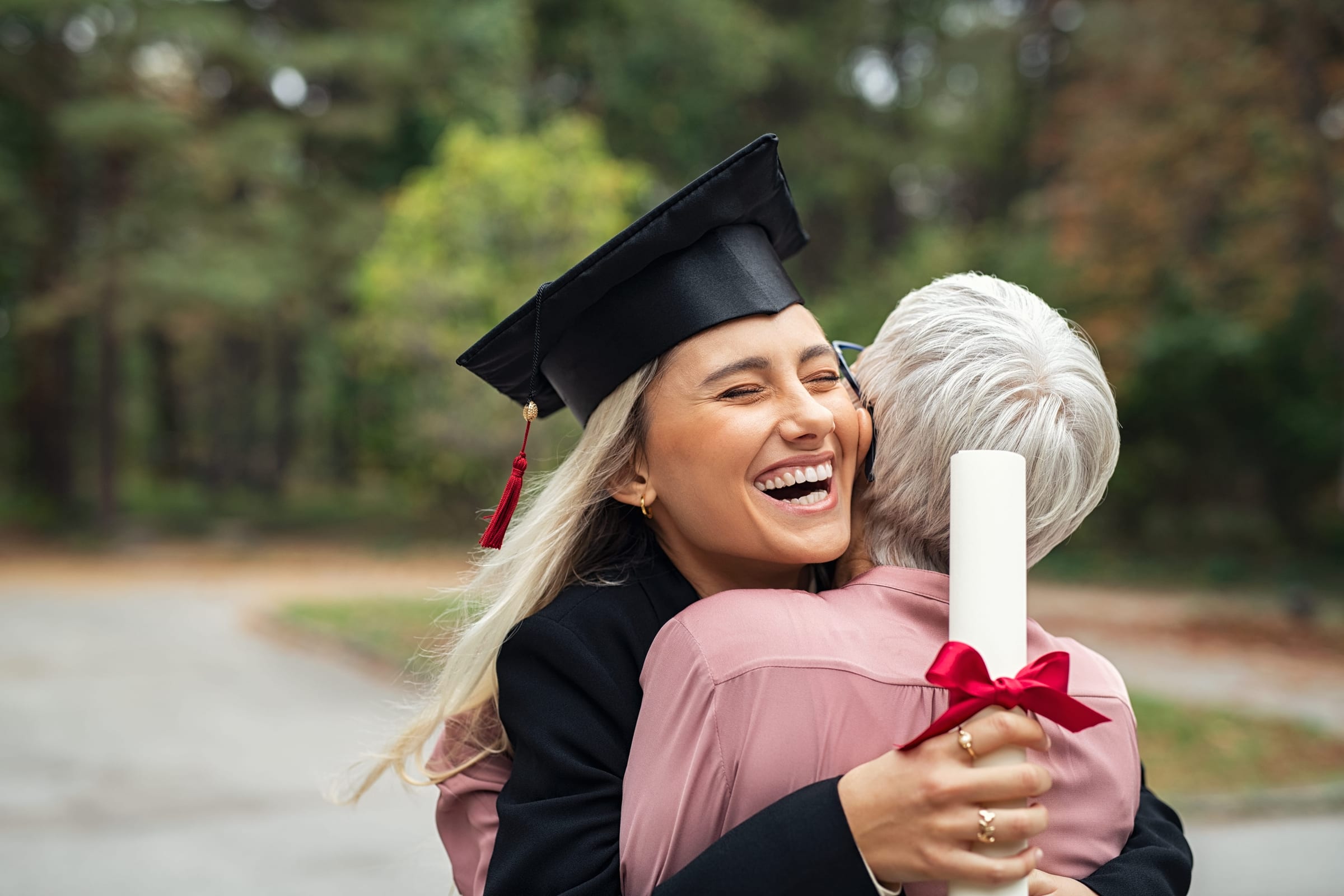 A graduate and her parent hugging in celebration on graduation day